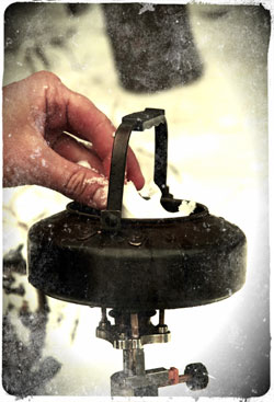 Melting snow with a camping kettle and gas camp stove for drinking water.